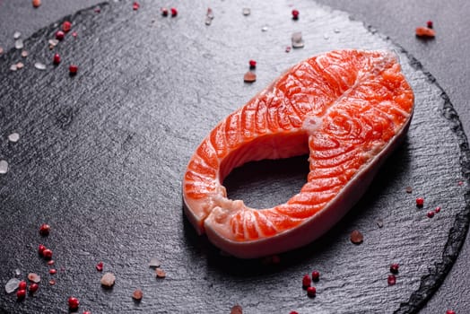 Raw trout red fish steak served with herbs and lemon and olive oil on a dark background. Cooking Salmon, sea food. Healthy eating concept