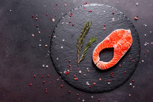 Raw trout red fish steak served with herbs and lemon and olive oil on a dark background. Cooking Salmon, sea food. Healthy eating concept