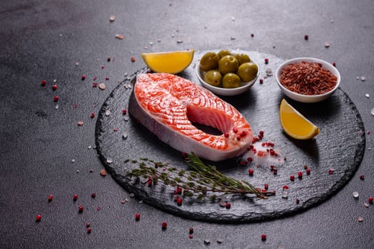 Raw trout red fish steak served with herbs and lemon and olive oil on a dark background. Cooking Salmon, sea food. Healthy eating concept