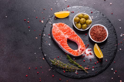 Raw trout red fish steak served with herbs and lemon and olive oil on a dark background. Cooking Salmon, sea food. Healthy eating concept