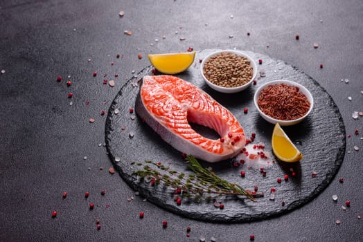 Raw trout red fish steak served with herbs and lemon and olive oil on a dark background. Cooking Salmon, sea food. Healthy eating concept