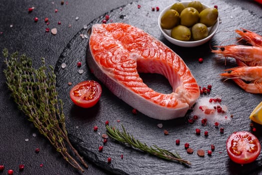 Raw trout red fish steak served with herbs and lemon and olive oil on a dark background. Cooking Salmon, sea food. Healthy eating concept