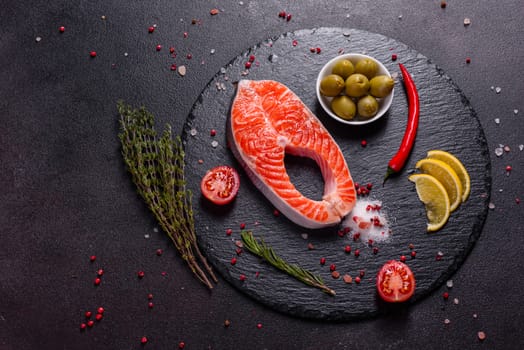 Raw trout red fish steak served with herbs and lemon and olive oil on a dark background. Cooking Salmon, sea food. Healthy eating concept