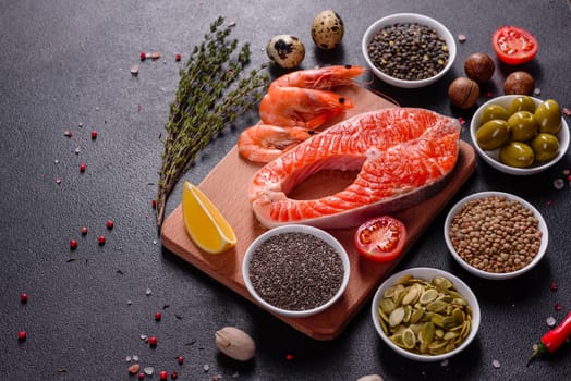 Raw trout red fish steak served with herbs and lemon and olive oil on a dark background. Cooking Salmon, sea food. Healthy eating concept