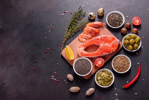 Raw trout red fish steak served with herbs and lemon and olive oil on a dark background. Cooking Salmon, sea food. Healthy eating concept