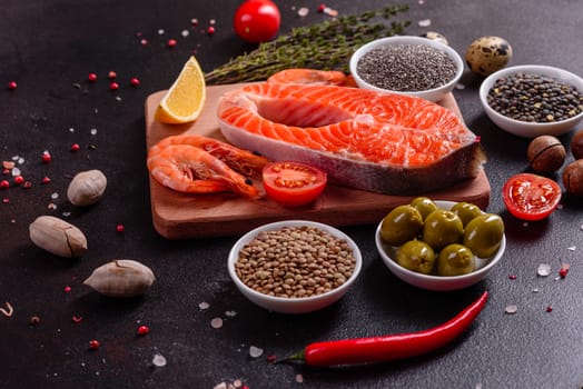 Raw trout red fish steak served with herbs and lemon and olive oil on a dark background. Cooking Salmon, sea food. Healthy eating concept
