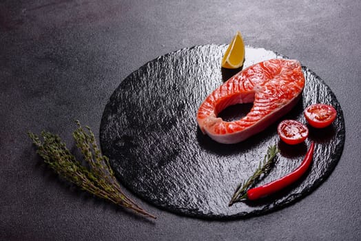 Raw trout red fish steak served with herbs and lemon and olive oil on a dark background. Cooking Salmon, sea food. Healthy eating concept