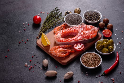 Raw trout red fish steak served with herbs and lemon and olive oil on a dark background. Cooking Salmon, sea food. Healthy eating concept