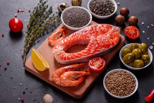 Raw trout red fish steak served with herbs and lemon and olive oil on a dark background. Cooking Salmon, sea food. Healthy eating concept
