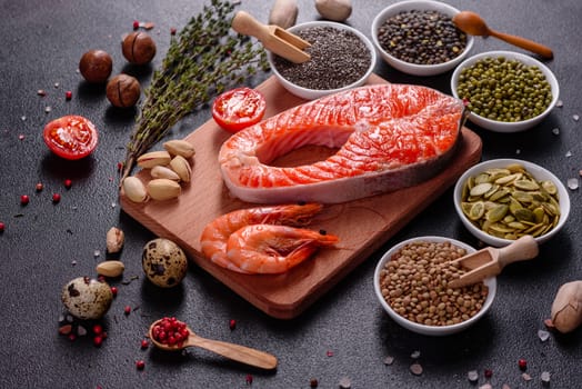 Raw trout red fish steak served with herbs and lemon and olive oil on a dark background. Cooking Salmon, sea food. Healthy eating concept