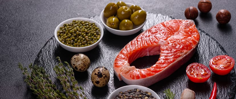 Raw trout red fish steak served with herbs and lemon and olive oil on a dark background. Cooking Salmon, sea food. Healthy eating concept