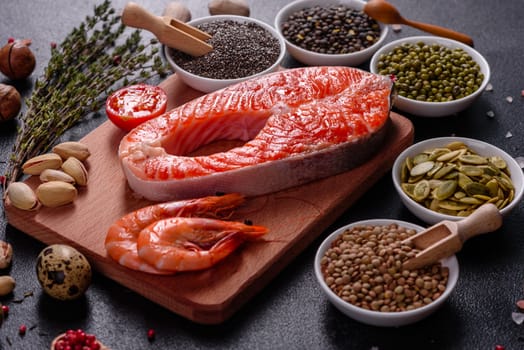 Raw trout red fish steak served with herbs and lemon and olive oil on a dark background. Cooking Salmon, sea food. Healthy eating concept