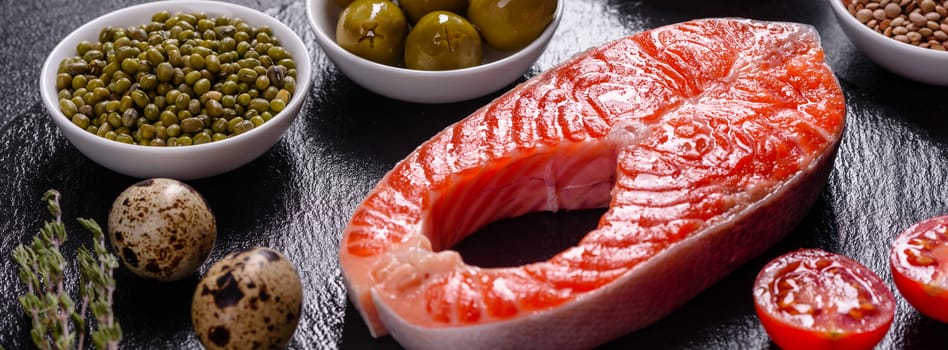 Raw trout red fish steak served with herbs and lemon and olive oil on a dark background. Cooking Salmon, sea food. Healthy eating concept