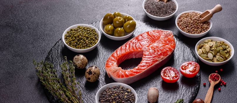 Raw trout red fish steak served with herbs and lemon and olive oil on a dark background. Cooking Salmon, sea food. Healthy eating concept