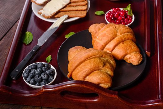 Delicious breakfast with fresh croissants and ripe berries on a beautiful wooden table