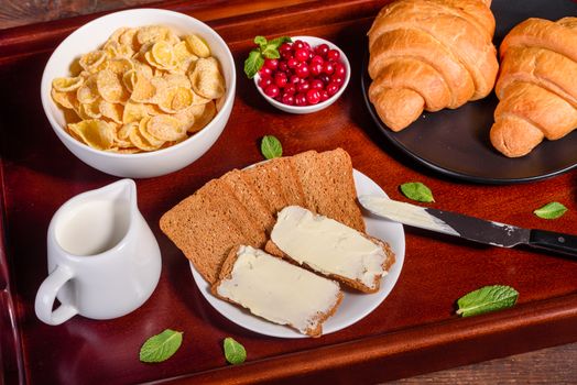 Delicious breakfast with fresh croissants and ripe berries on a beautiful wooden table