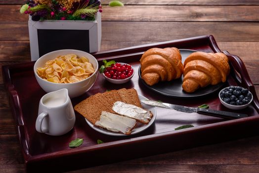 Delicious breakfast with fresh croissants and ripe berries on a beautiful wooden table