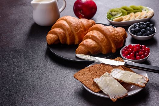Delicious breakfast with fresh croissants and ripe berries on a beautiful wooden table