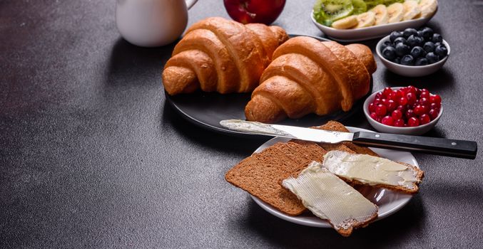 Delicious breakfast with fresh croissants and ripe berries on a beautiful wooden table