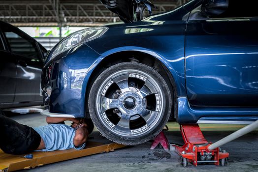 Car mechanic or serviceman checking a car engine for fix and repair problem at car garage or repair shop