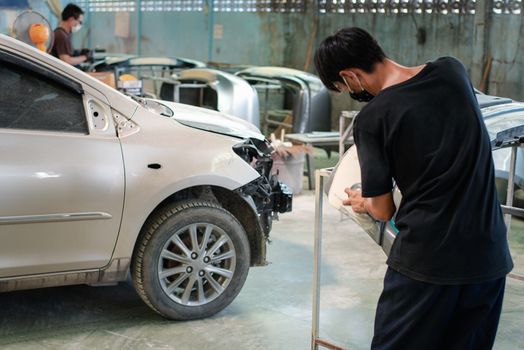 Denter or car mechanic serviceman check and fix body work and fiber bumper body part for fix and repair problem at car garage or repair shop