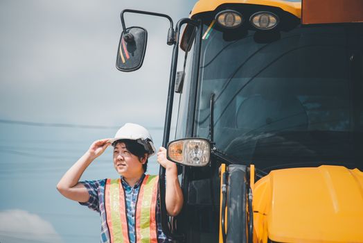 Asian woman civil construction engineer worker or architect with helmet and safety vest happy working and loader backhoe at a building or construction site