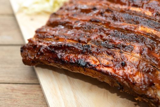 Roasted Pork Spare Ribs Barbecue or Pork Ribs with BBQ Sauce on wooden cutting board in kitchen at Thai street food market or restaurant