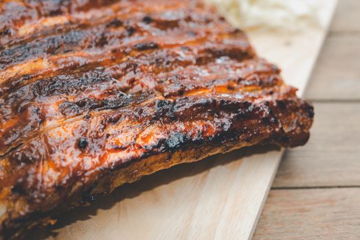 Roasted Pork Spare Ribs Barbecue or Pork Ribs with BBQ Sauce on wooden cutting board in kitchen at Thai street food market or restaurant