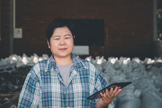 Asian woman smart farmer agriculturist happy at a Fertilizer composting plant with Organic Fertilizer, Compost (Aerobic Microorganisms) from animal waste for use in the organic agriculture industry