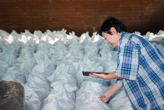 Asian woman smart farmer agriculturist working at Fertilizer composting plant with Organic Fertilizer, Compost (Aerobic Microorganisms) from animal waste for use in the organic agriculture industry