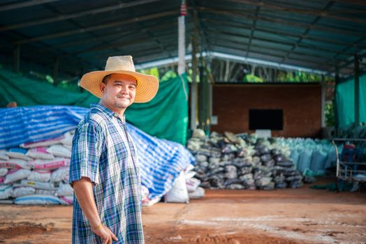 Asian man farmer agriculturist happy at a Fertilizer composting plant with Organic Fertilizer, Compost (Aerobic Microorganisms) from animal waste for use in the organic agriculture industry