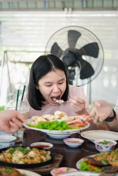 Asian pretty cute woman eating thai food with rice and many food on dining table in restaurant with happy and enjoy emotion