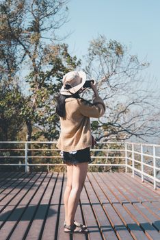 Asian pretty cute woman with hat relax and use smartphone at seaside city landscape viewpoint on mountain with happy and freedom emotion in concept travel, vacation, leisure in life