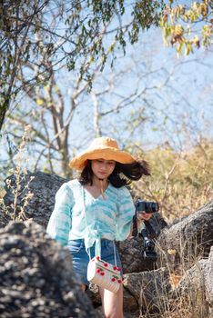 Asian pretty cute woman short jeans with hat hiking in forest on mountain with cliff with happy and freedom emotion in concept travel, active lifestyle, vacation, overcome obstacles in life