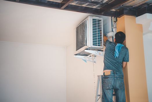 Worker to cleaning coil cooler of air conditioner by water for clean a dust on the wall in customer home when maintenance service