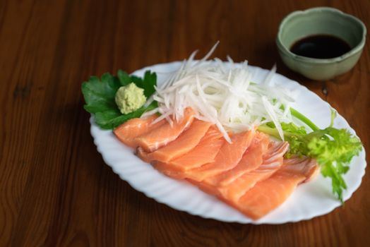 Japanese food delicacy consisting sashimi salmon of very fresh raw salmon fish sliced into thin pieces serving with radish sliced in japan restaurant