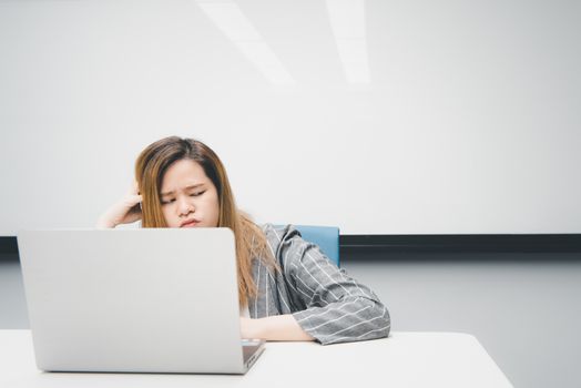 Asian woman is student,businesswoman working by computer notebook, laptop in office meeting room with whiteboard background with thinking, concentrate emotion in concept working woman,success in life