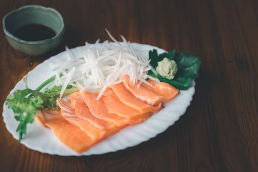 Japanese food delicacy consisting sashimi salmon of very fresh raw salmon fish sliced into thin pieces serving with radish sliced in japan restaurant