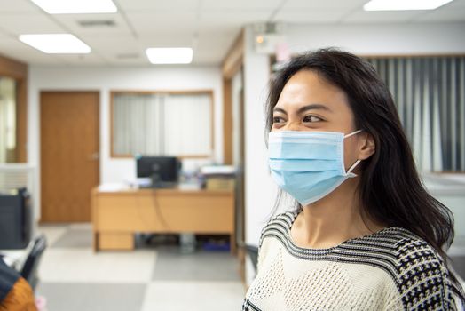 Asian pretty woman wearing mask respiratory protection mask against epidemic flu covid19 or corona virus from wuhan in office with fear emotion in concept illness, outbreak, healthcare in life