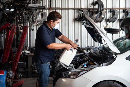 Car mechanic or serviceman cleaning the car engine after checking a car engine for fix and repair problem at car garage or repair shop