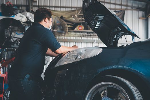 Car mechanic or serviceman checking a car engine for fix and repair problem at car garage or repair shop