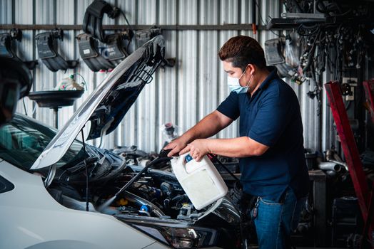 Car mechanic or serviceman cleaning the car engine after checking a car engine for fix and repair problem at car garage or repair shop