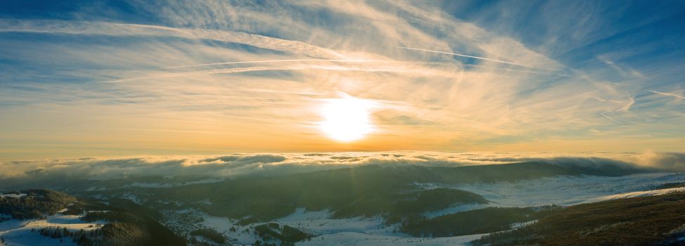 Aerial view. Aerial drone view of a winter landscape. Snow covered forest. Dramatic gold sunset sky.