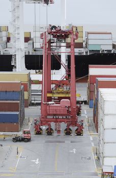 Cargo Containers Truck And A Crane In Storage Area Of Freight Port Terminal