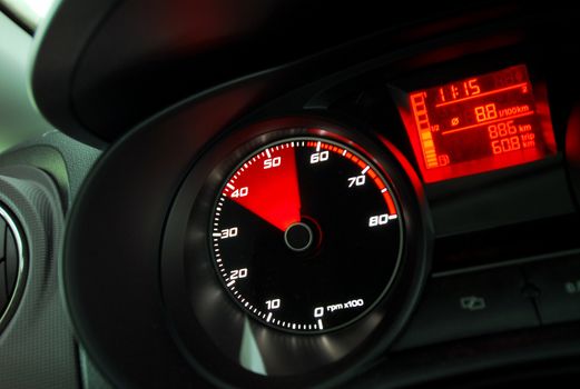 Tachometer reaching the red zone, sports car inside