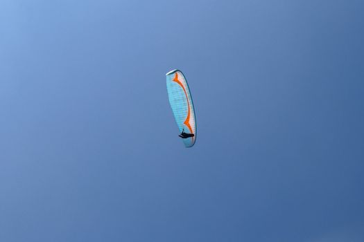 Paragliding in the sky. Paraglider flying in bright sunny day. Beautiful paraglider in flight on a turquise background. Concept of active lifestyle and extreme sport adventure. Isolated.