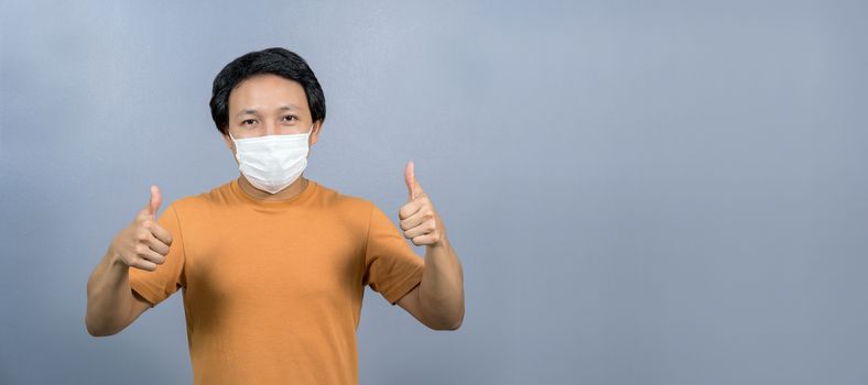 Portrait of asian man wearing face surgical mask with thumbs up like on blue color background, Coronavirus pandemic, covid19 outbreak, social distancing and responsibility, healthcare and protection