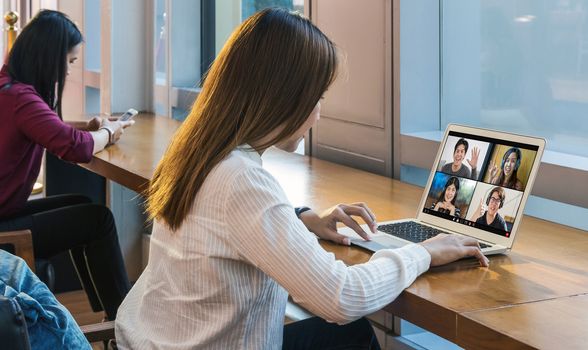 back side of Asian Business woman meeting with teamwork colleague sharing and voting topic in video conference when Coronavirus outbreak, Covid-19 pandemic,remote online meeting and new normal concept