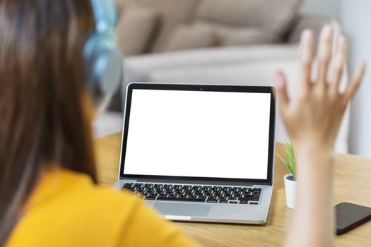 Rear View of Asian Business woman using laptop and say hello to white screen in modern of house when Coronavirus outbreak, Covid-19 pandemic, online meeting, Social distancing and new normal concept