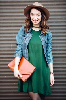 Romantic and beautiful brunette girl in brown hat lokking at camera and posing at street. Attractive woman with wavy hair, perfect make up, walking after beauty salon. Street fashion.